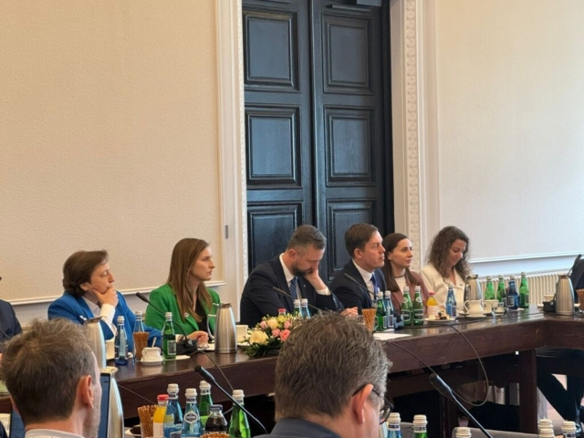 Uczestnicy Forum siedzą przy stole  podczas debaty